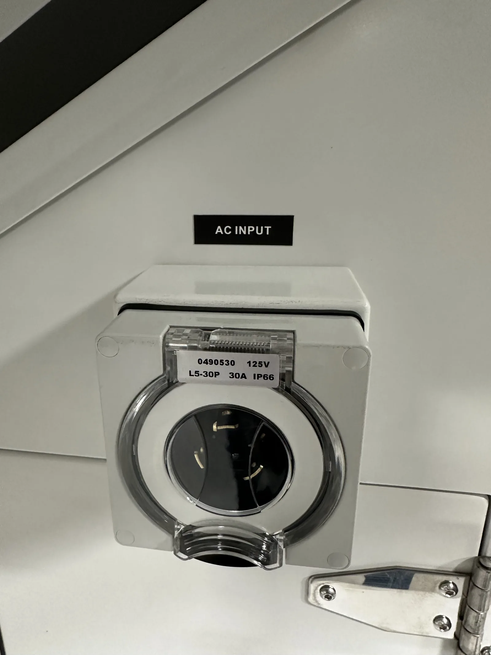 The 30 A twist-lock shore-power inlet on the side of the cabinet